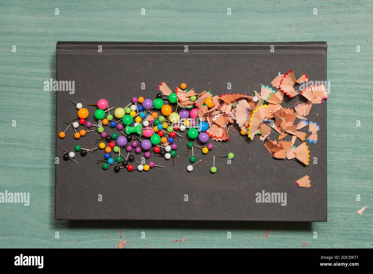 Colorful scraps of school supplies on a black cover book on a wooden table. Stock Photo