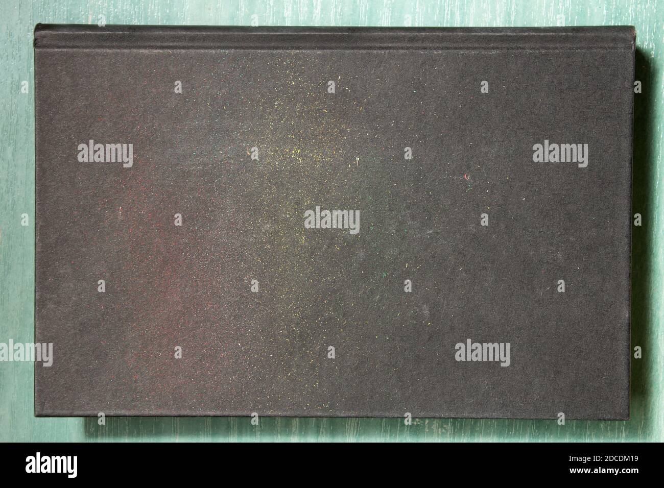 Black book cover with colored paint remnants and pigmented pencil leads