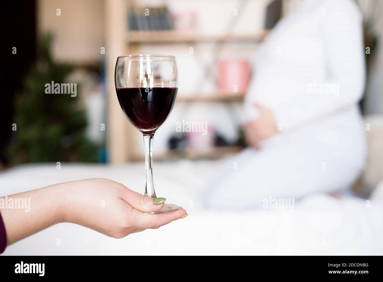 Pregnant woman keeping glass of wine. Future mother drinking alcohol