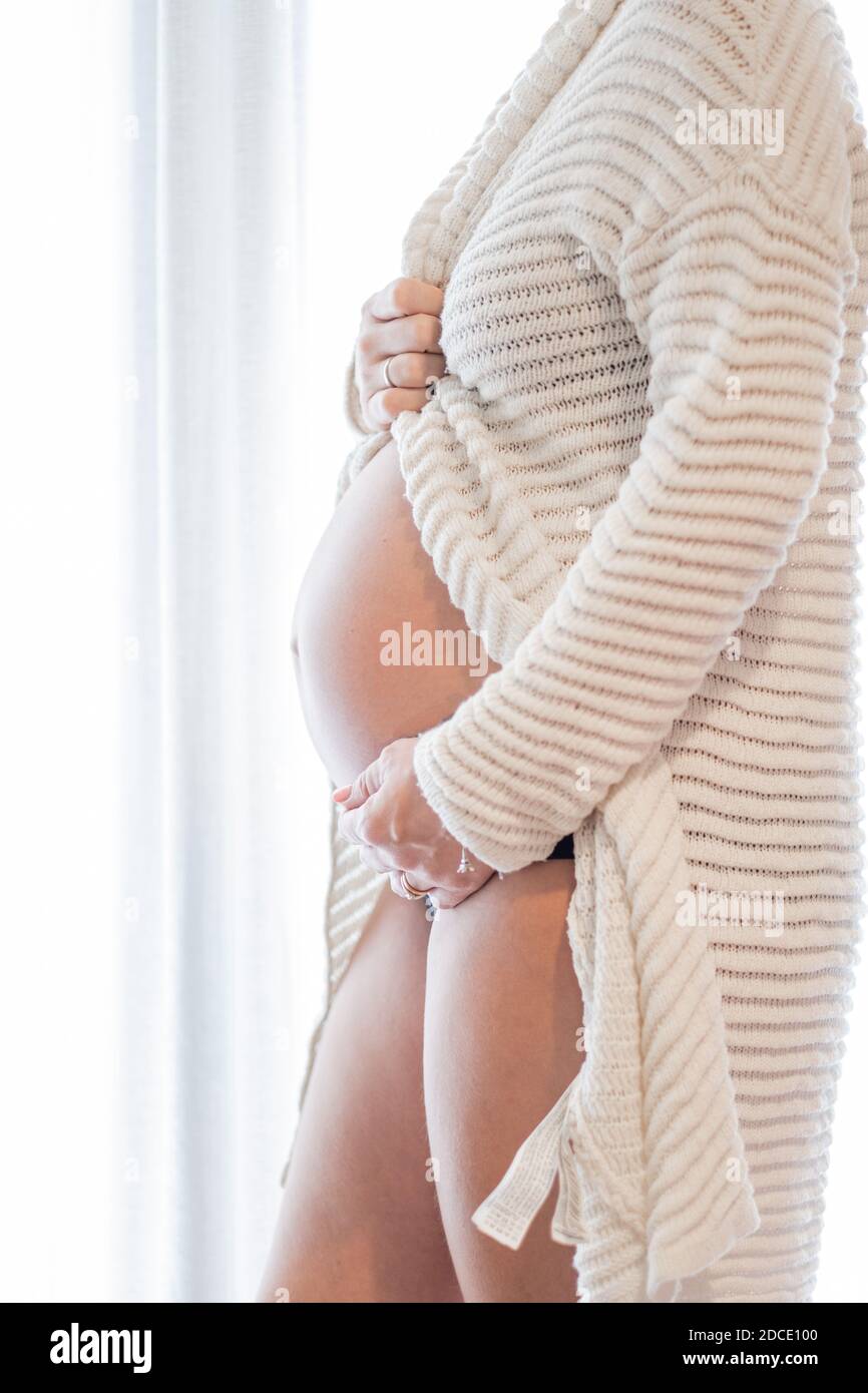 Pregnant woman at home while taking care of her child. The young expecting mother holding baby in pregnant belly. Maternity prenatal care Stock Photo