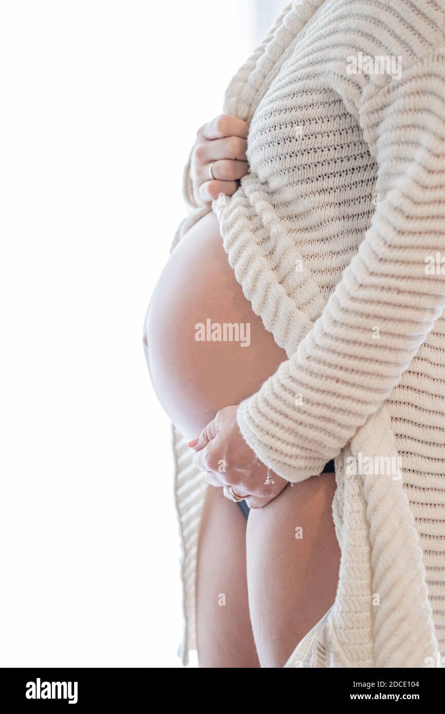 Pregnant woman at home while taking care of her child. The young expecting mother holding baby in pregnant belly. Maternity prenatal care and woman pr Stock Photo
