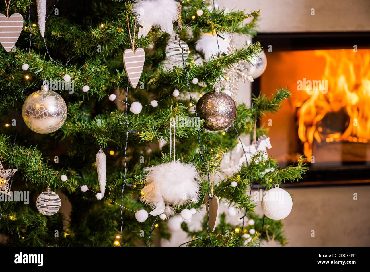 Light type of different Christmas decoration on the tree with flames of fireplace in background Stock Photo