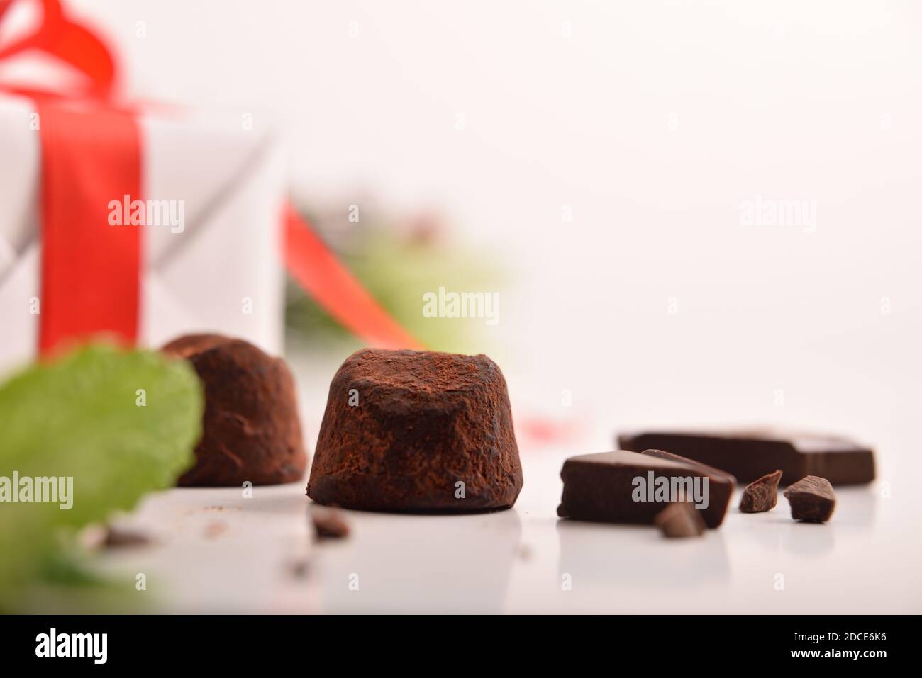Christmas composition with chocolate truffles on white table with gift and Christmas decoration. Front view. Horizontal composition. Stock Photo