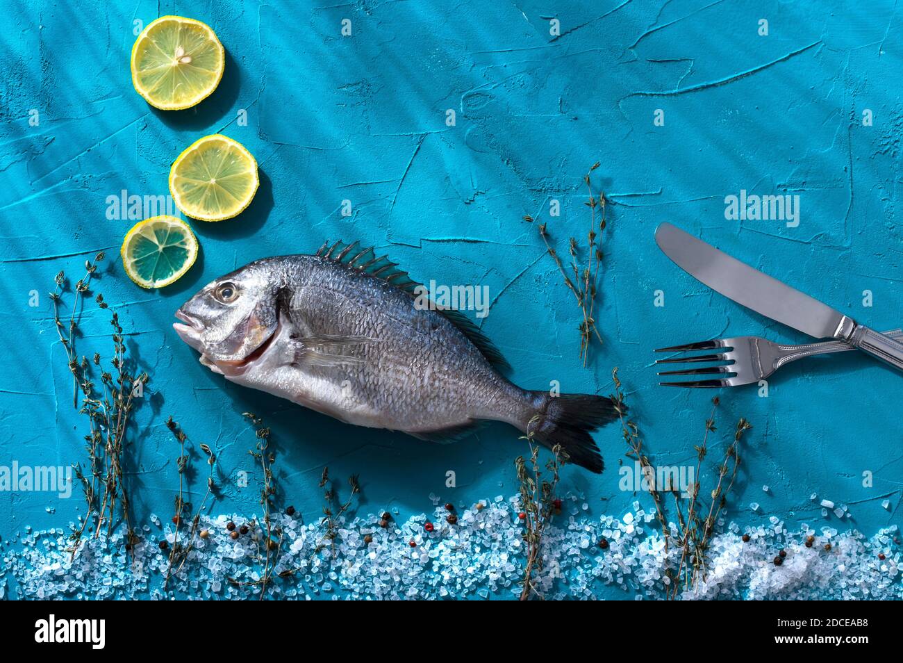 Concept scene of fresh raw sea bream fish decorated with lemon slices ...