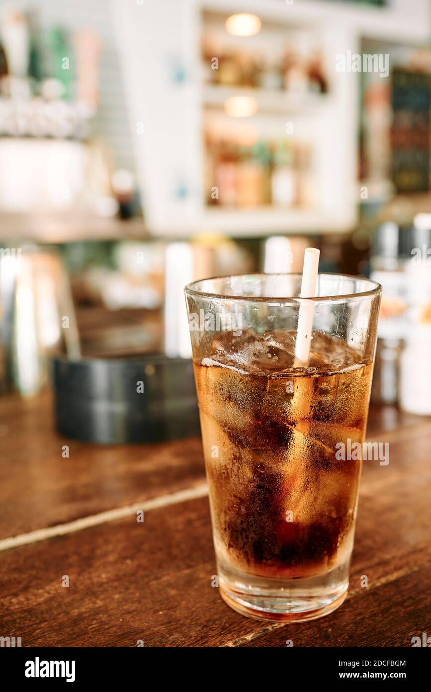 Tall glass of Coke-a-Cola or Pepsi on a wooden bar top in a resort bar in Seaside Florida, USA. Stock Photo