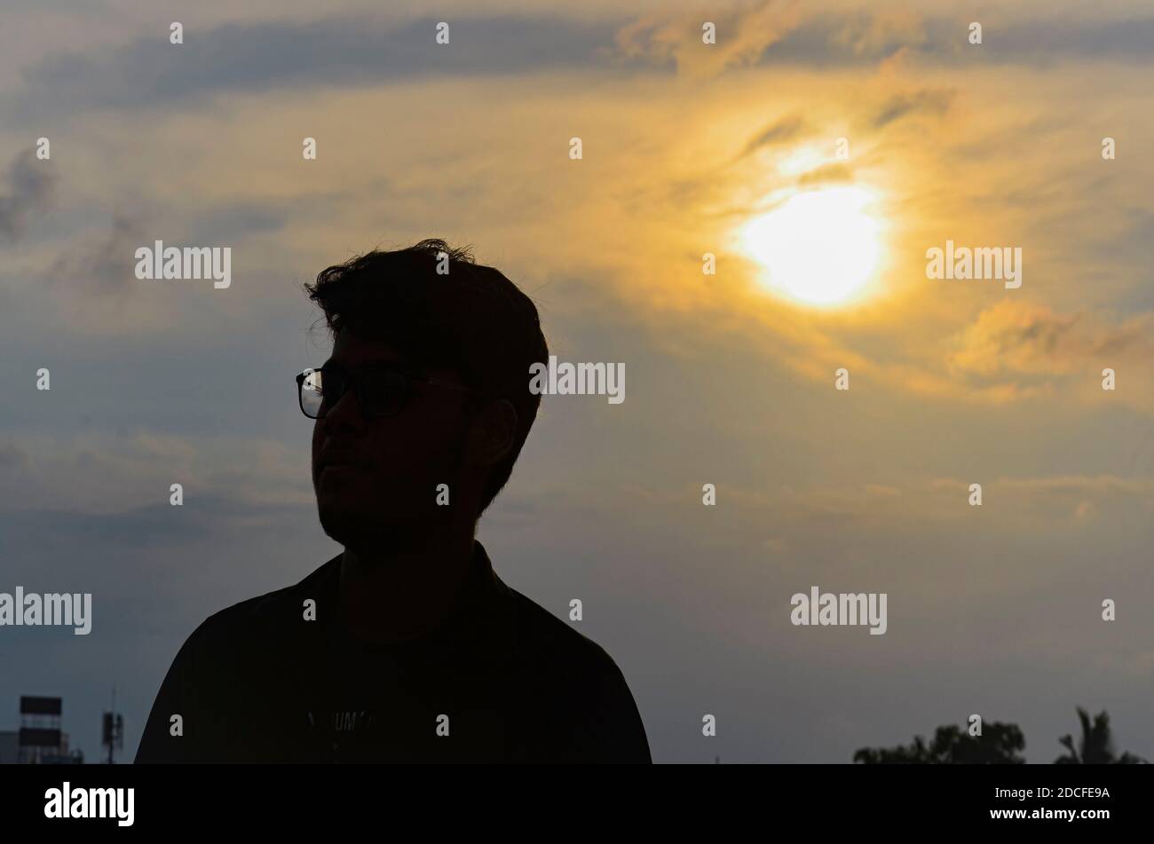 Silhouette of a man standing with sunset on background with cloudy sky. Shot by MNZR. Nikon DSLR. Stock Photo
