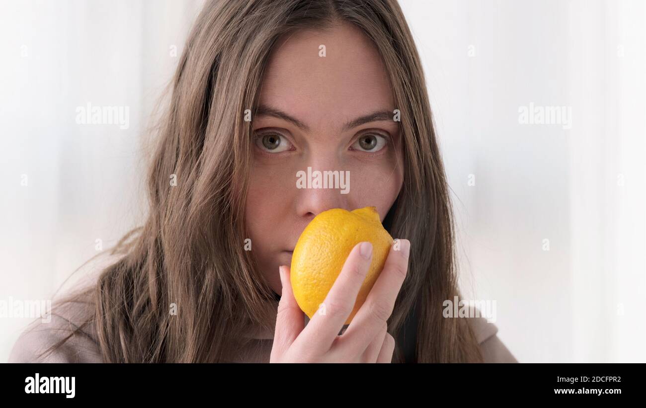 Woman sniffs lemon and does not smell Stock Photo