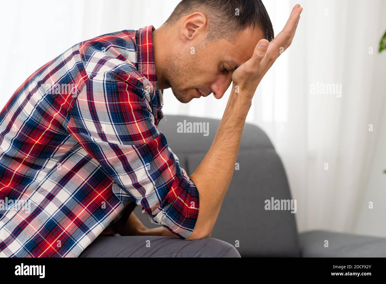 Thoughtful young man in the living room Stock Photo - Alamy