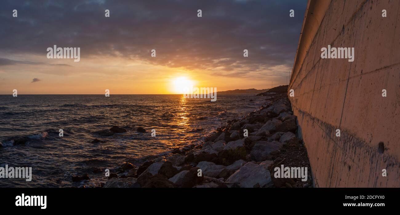 Concrete wall along the coast, with N340 highway above, sunset, El Faro de Calaburras, Andalusia, Spain. Stock Photo