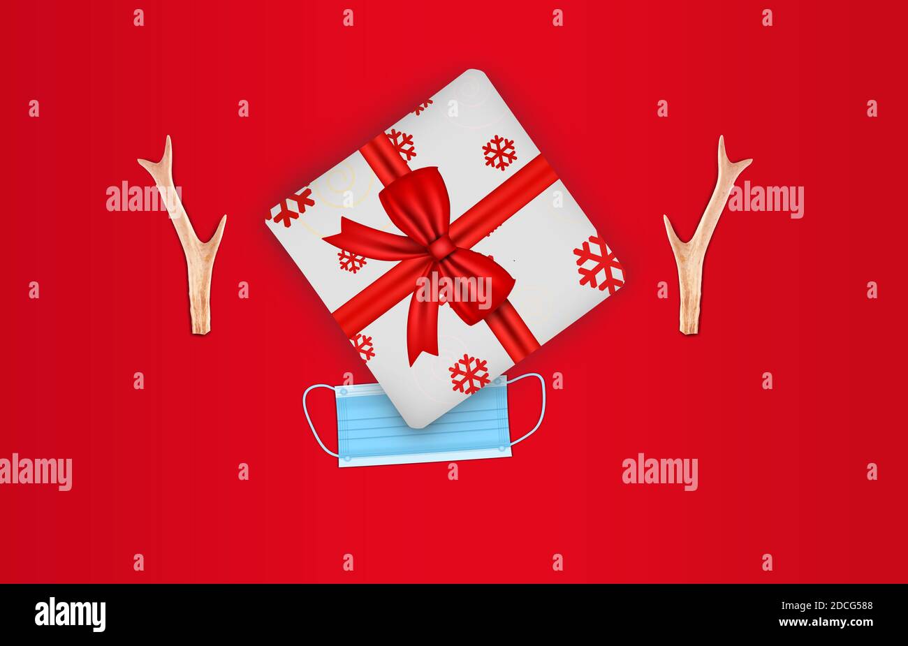 Pandemic Festive christmas concept. Gift box (top view) with deer horn and face mask decoration. Flat lay on red holiday background Stock Photo