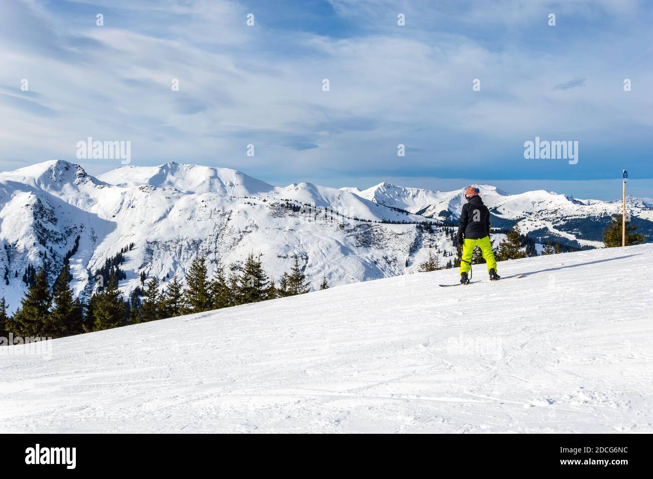 Snowboarder on slope against mountains and sunset in winter ski resort Zell am See in the Alps, Austria. Kitzsteinhorn mountain range seen from Schmit Stock Photo