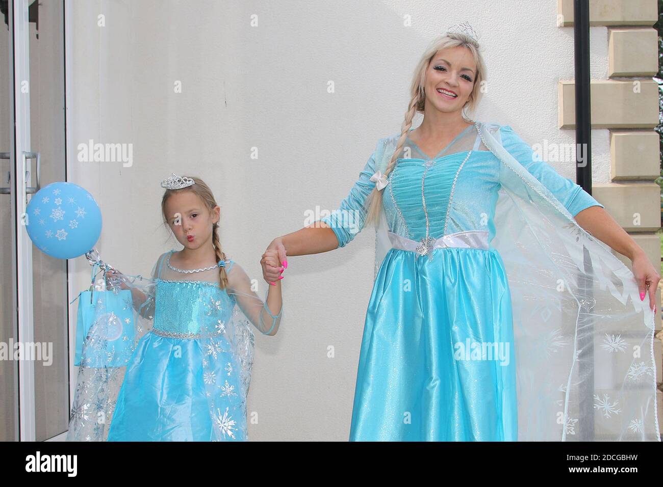 Costume fancy dress characters. Woman dressed as Elsa from frozen with a little girls dressed as a princess Stock Photo