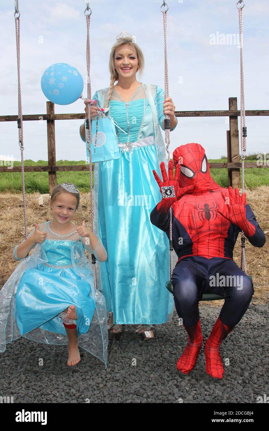 Costume fancy dress characters, Elsa, little princess, and Spiderman on  swing in garden Stock Photo - Alamy