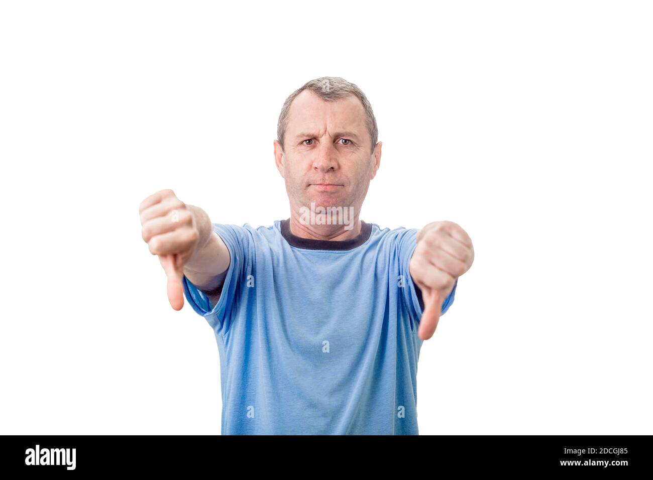 Displeased middle aged man showing thumbs down, negative gesture and bad feedback, looking to camera isolated on white wall background. Stock Photo