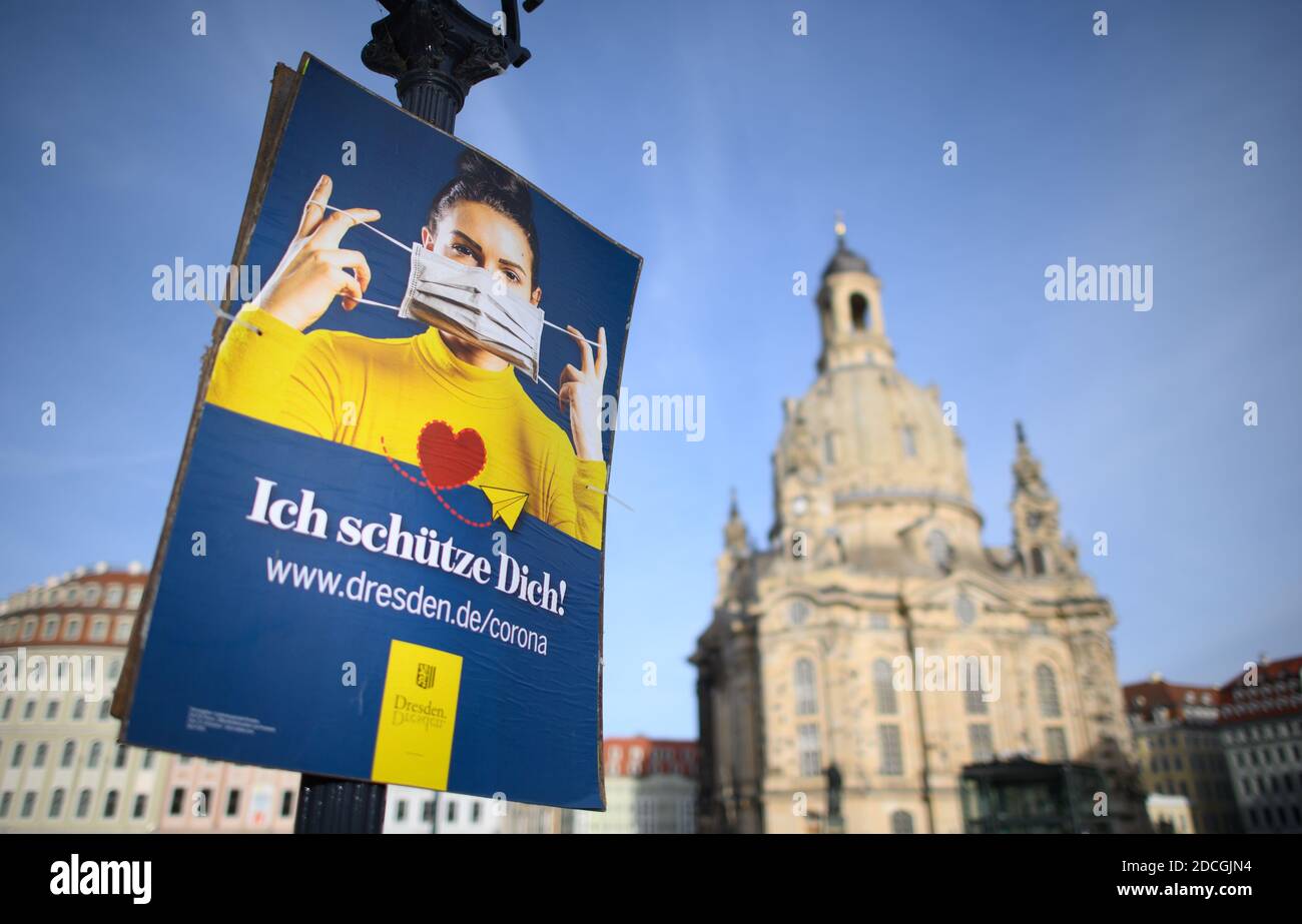 Dresden, Germany. 21st Nov, 2020. The official poster of the state capital Dresden, which points out the use of mouth and nose covers, hangs on a lantern on the Neumarkt in front of the Frauenkirche. The federal and state governments have decided on a partial lockdown. Among other things, restaurants, leisure facilities and cultural institutions will have to close. This still includes the distance requirement and the obligation to wear masks. Credit: Robert Michael/dpa-Zentralbild/dpa/Alamy Live News Stock Photo