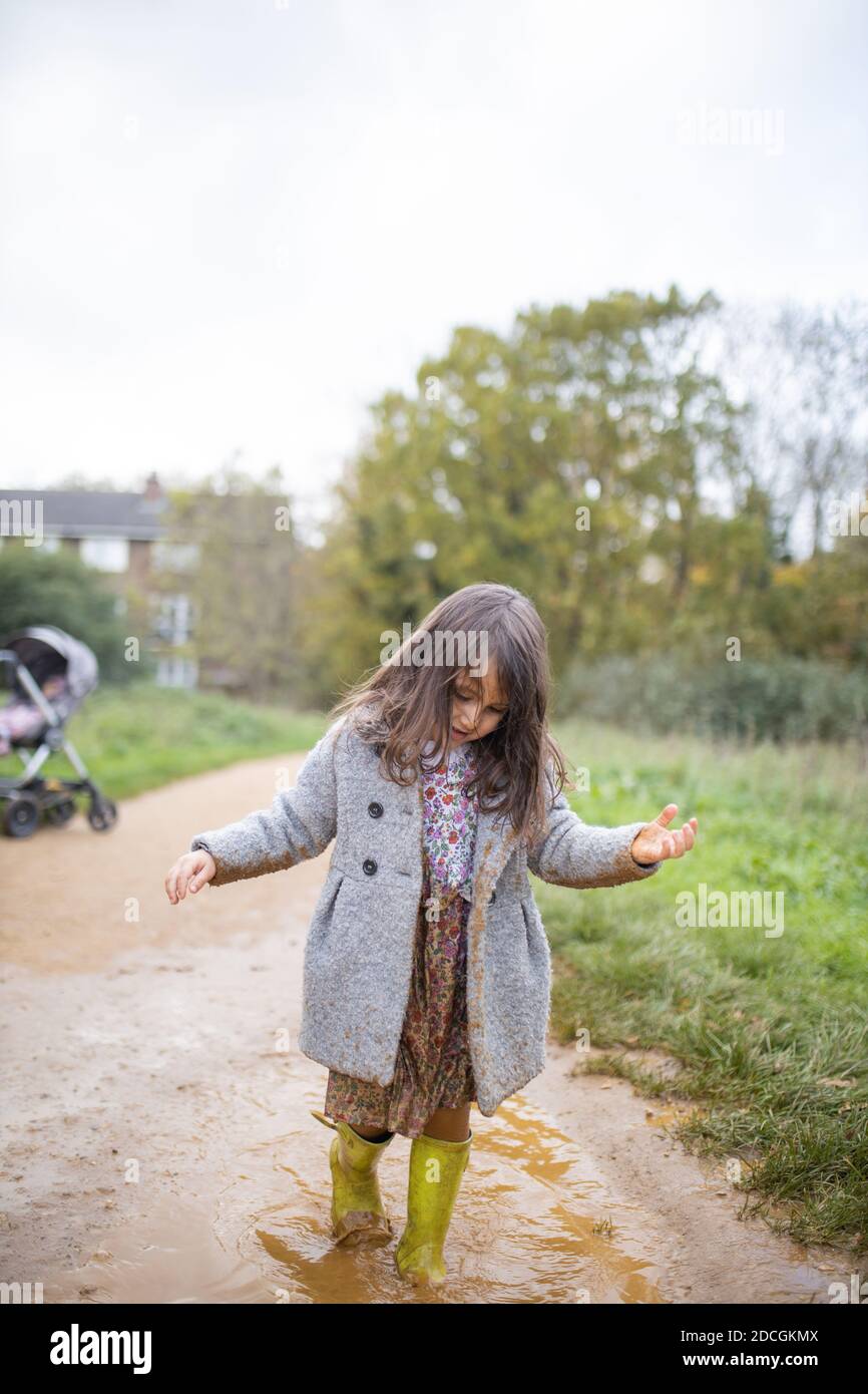 Happy little girl calmly walking through a muddy puddle Stock Photo Alamy