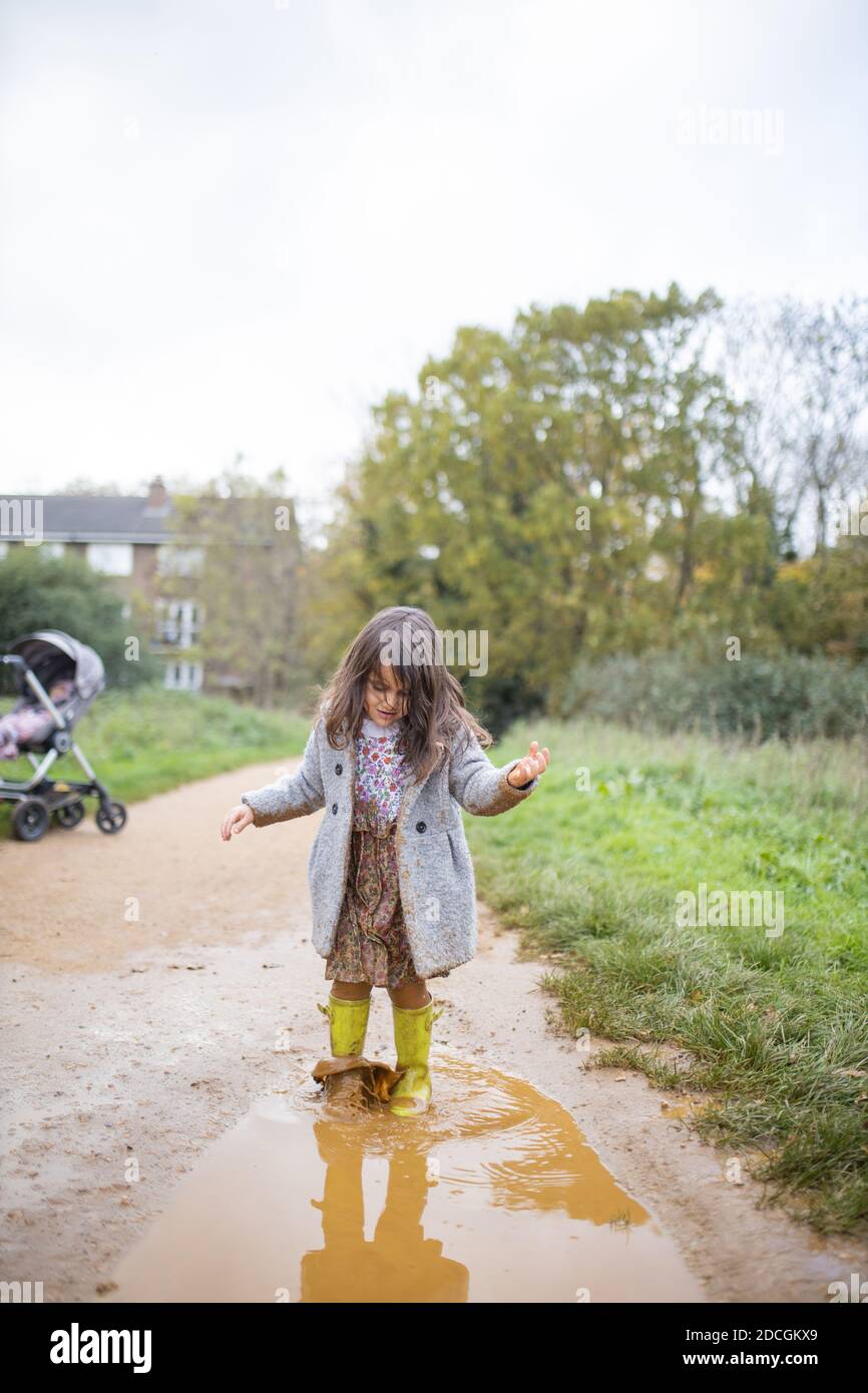 Happy little girl calmly walking through a muddy puddle Stock Photo Alamy