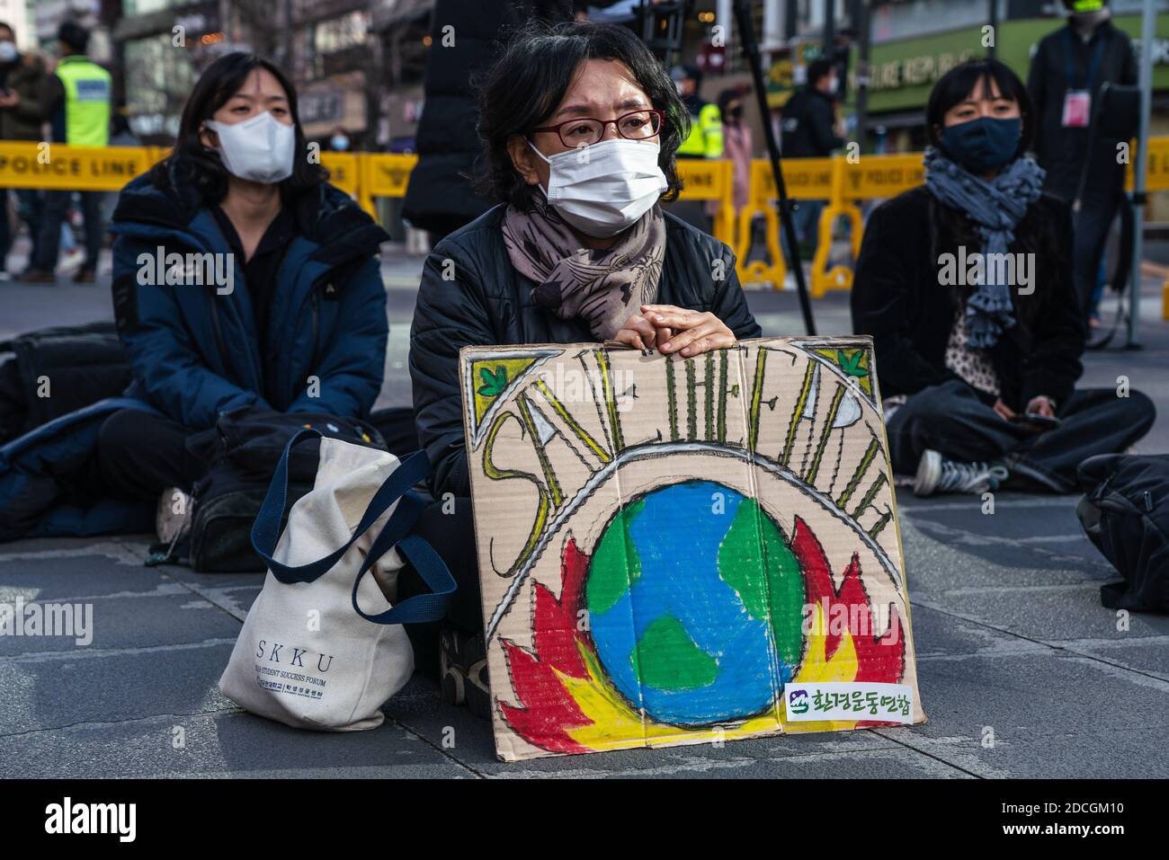 A protestor wearing a face mask displays a placard reading 'Save The Earth' during the climate crisis protest in Seoul.Climate Strikers gathered in a protest demanding the government to 'Work out Greenhouse Gases Plan 2050' in Seoul. Stock Photo