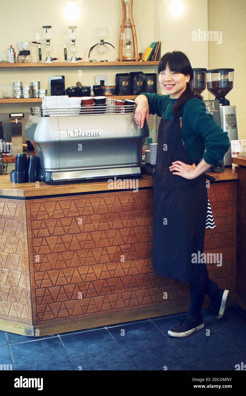 Great Britain / England / London /Asian female barista in front espresso machine in London coffee shop. Stock Photo
