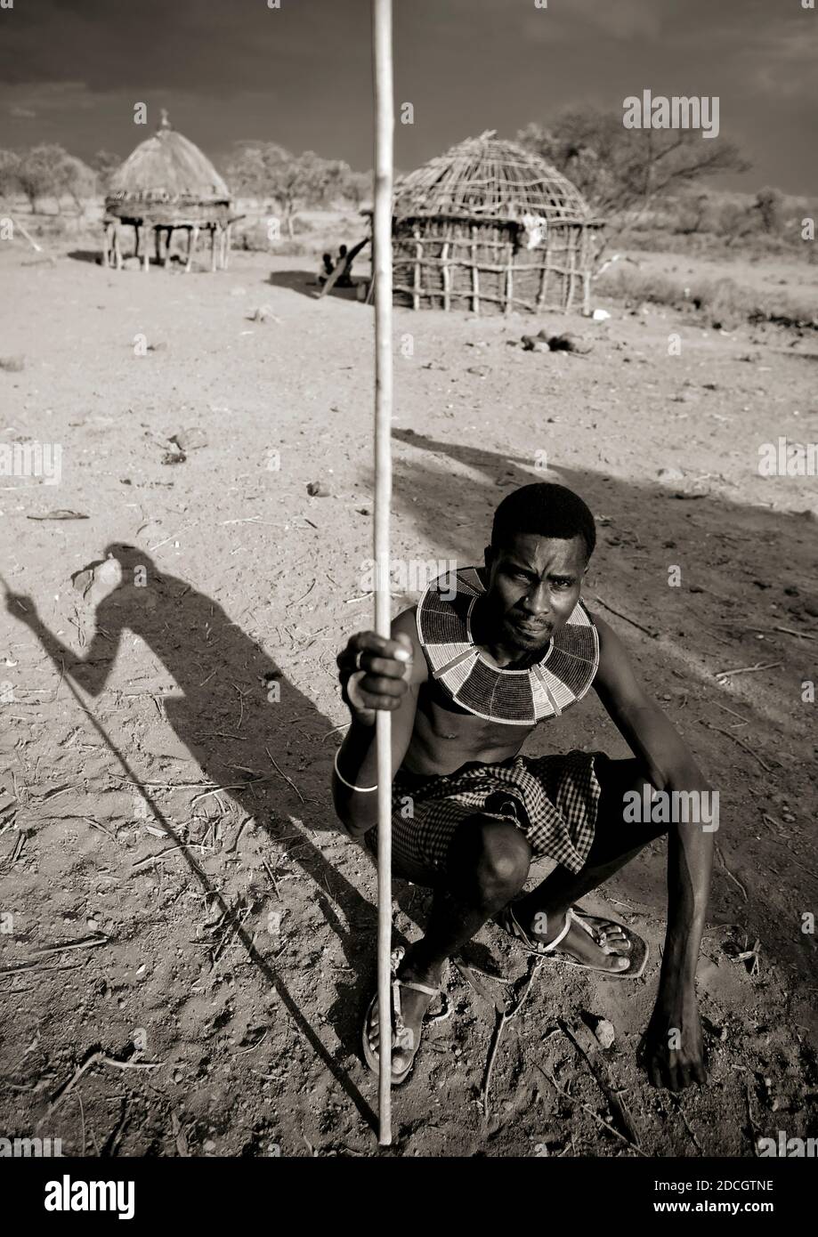 Portrait of a Pokot tribe man sit on his wooden pillow holding a spear, Baringo County, Baringo, Kenya Stock Photo