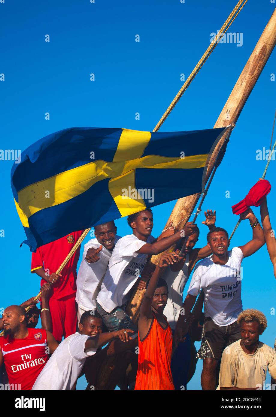 Swedish flagged dhow with crew cheering themselves, Lamu County, Lamu, Kenya Stock Photo