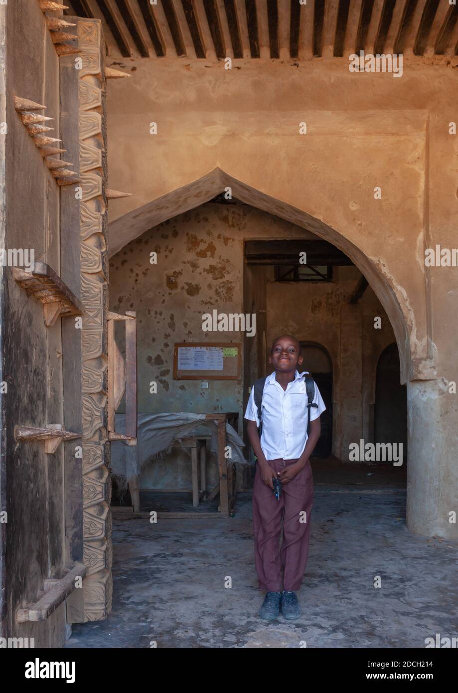 Kenyan pupil standing in front of a arved wooden front door, Lamu County, Lamu, Kenya Stock Photo