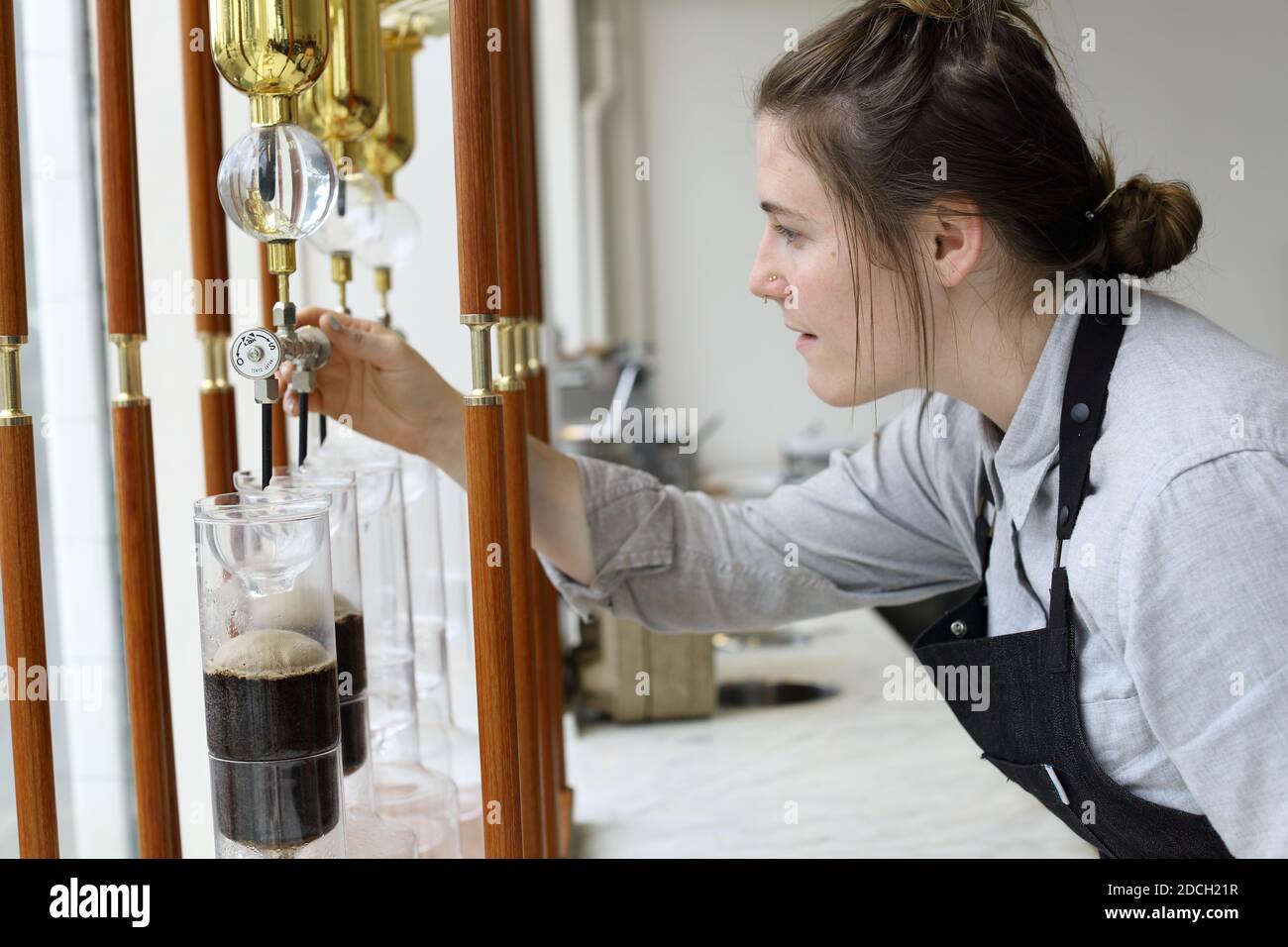 https://c8.alamy.com/comp/2DCH21R/united-states-california-san-francisco-female-barista-with-japanese-slow-dripper-with-brass-columns-glass-vessels-at-blue-bottle-coffee-2DCH21R.jpg