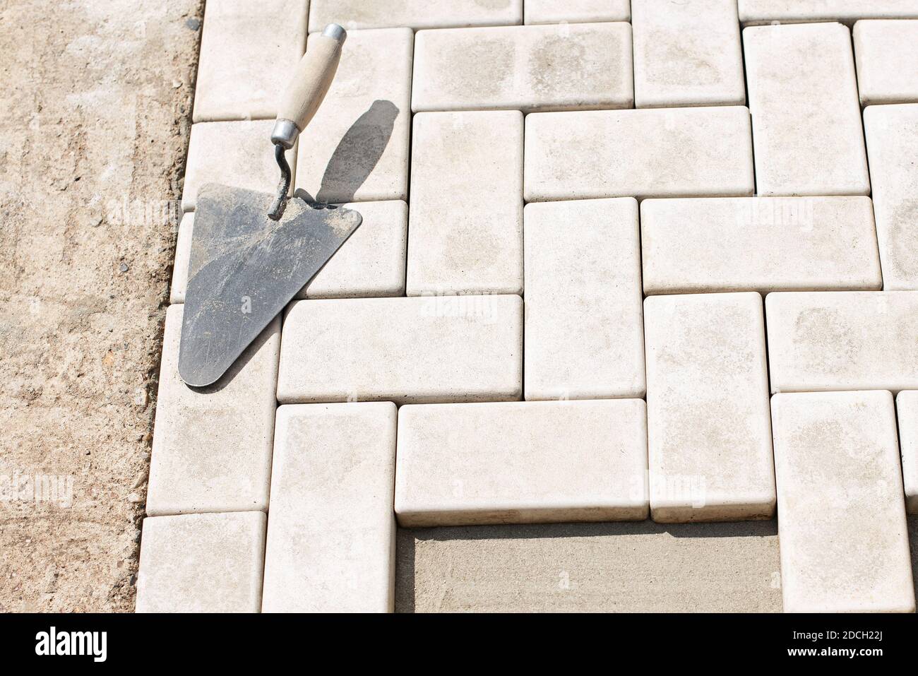 The master lays paving stones in layers. Garden brick pathway paving