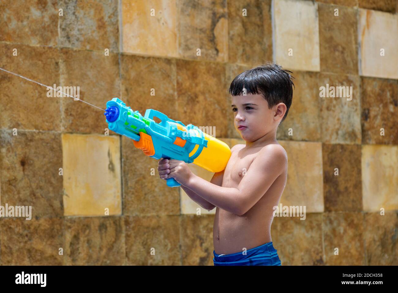 6 Year Old Child Playing With A Squirt Gun And His Dolls In The Pool