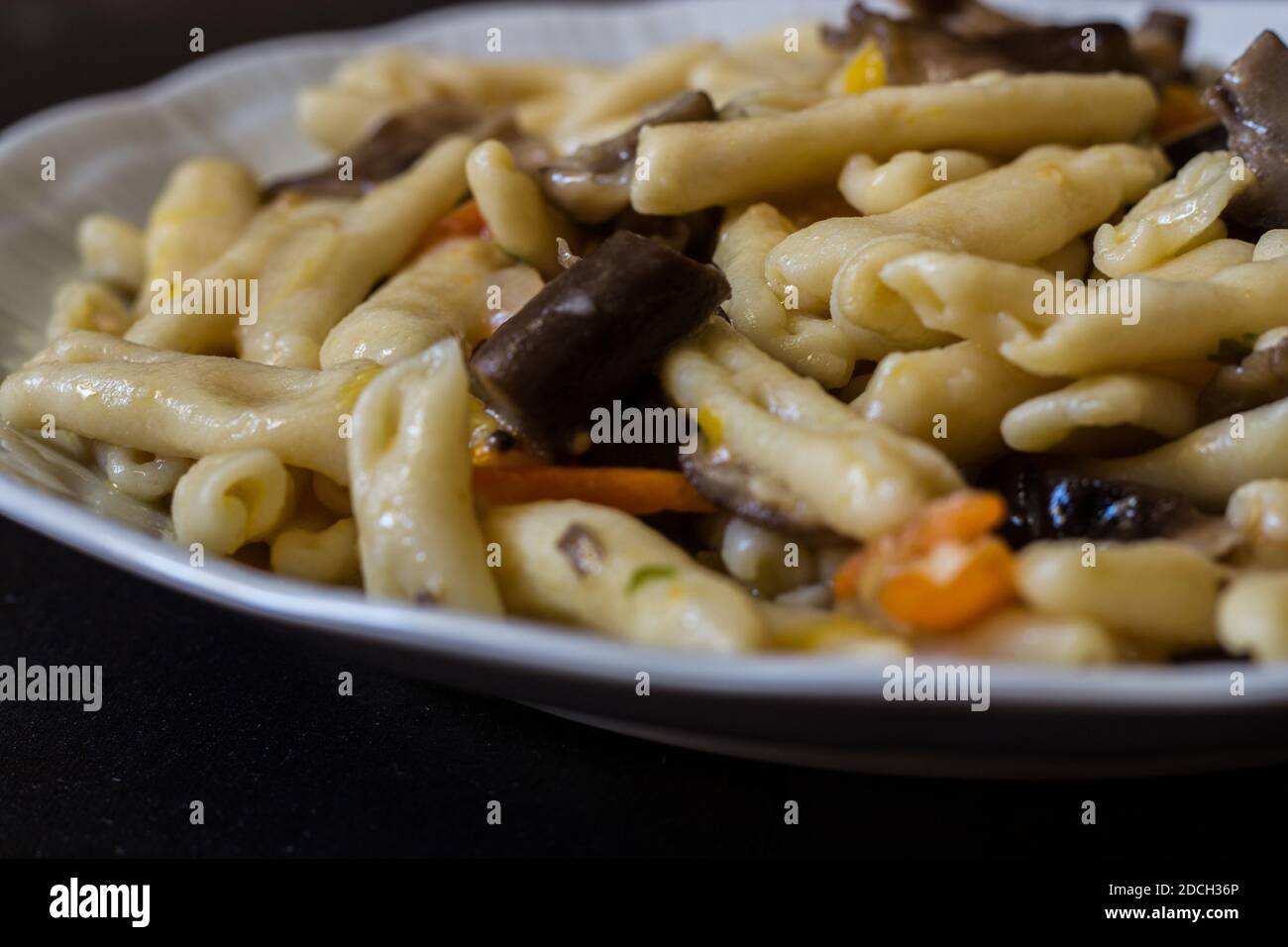 Cavatelli with pioppini mushrooms and yellow cherry tomatoes. Homemade pasta Stock Photo