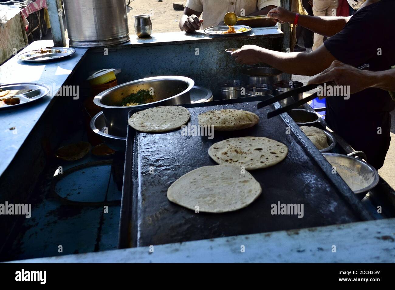Man making chapati. Indian street food stall. Roti with curry for breakfast on the street market in the morning. Stock Photo