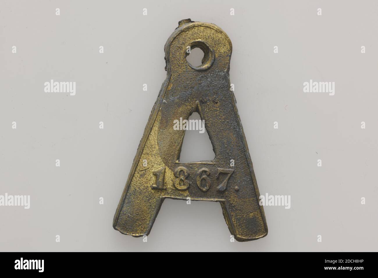 dog tag, Anonymous, 1867, minted, General: 3.1 x 2.5 x 0.2cm 31 x 25 x 2mm, Weight: 5.6g, Dog tag in the shape of the letter A of minted brass, provided with a round top from a hole. The year 1867 is engraved on the obverse. The reverse is embossed 894, 1880 Stock Photo