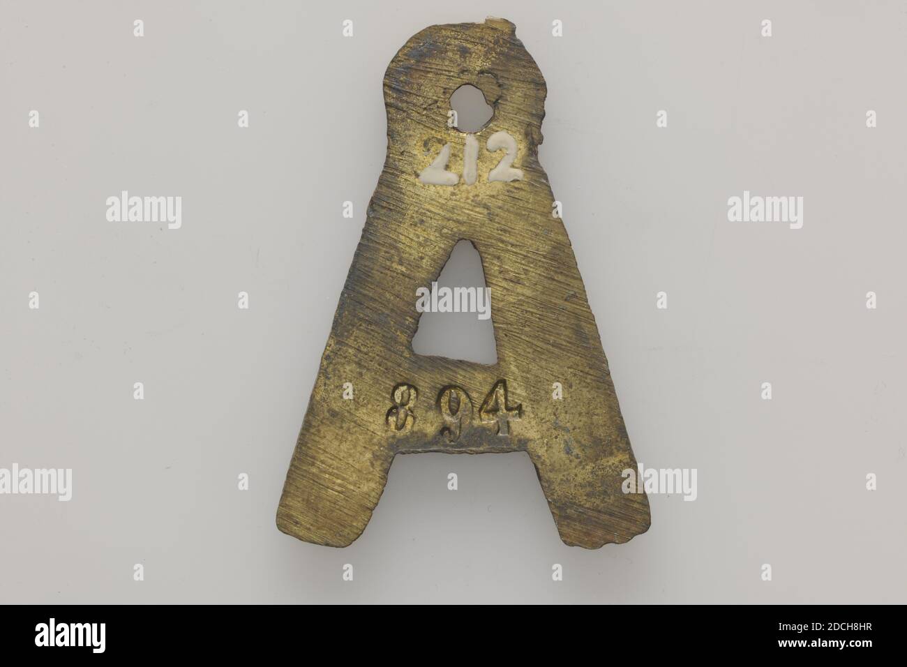 dog tag, Anonymous, 1867, minted, General: 3.1 x 2.5 x 0.2cm 31 x 25 x 2mm, Weight: 5.6g, Dog tag in the shape of the letter A of minted brass, provided with a round top from a hole. The year 1867 is engraved on the obverse. The reverse is embossed 894, 1880 Stock Photo