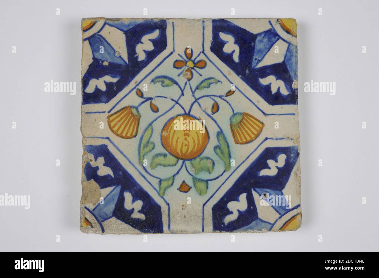 wall tile, Anonymous, first half of the 17th century, tin glaze, earthenware, General: 12.8 x 12.9 x 1.6cm (128 x 129 x 16mm), pomegranate, flower, Northern Netherlands, Earthenware wall tile covered with tin glaze. Multicolored painted in blue, orange brown, green and yellow with a stylized symmetrical pattern of a pomegranate and squares marigolds. The tile has a quarter star as corner motif, 1985 Stock Photo