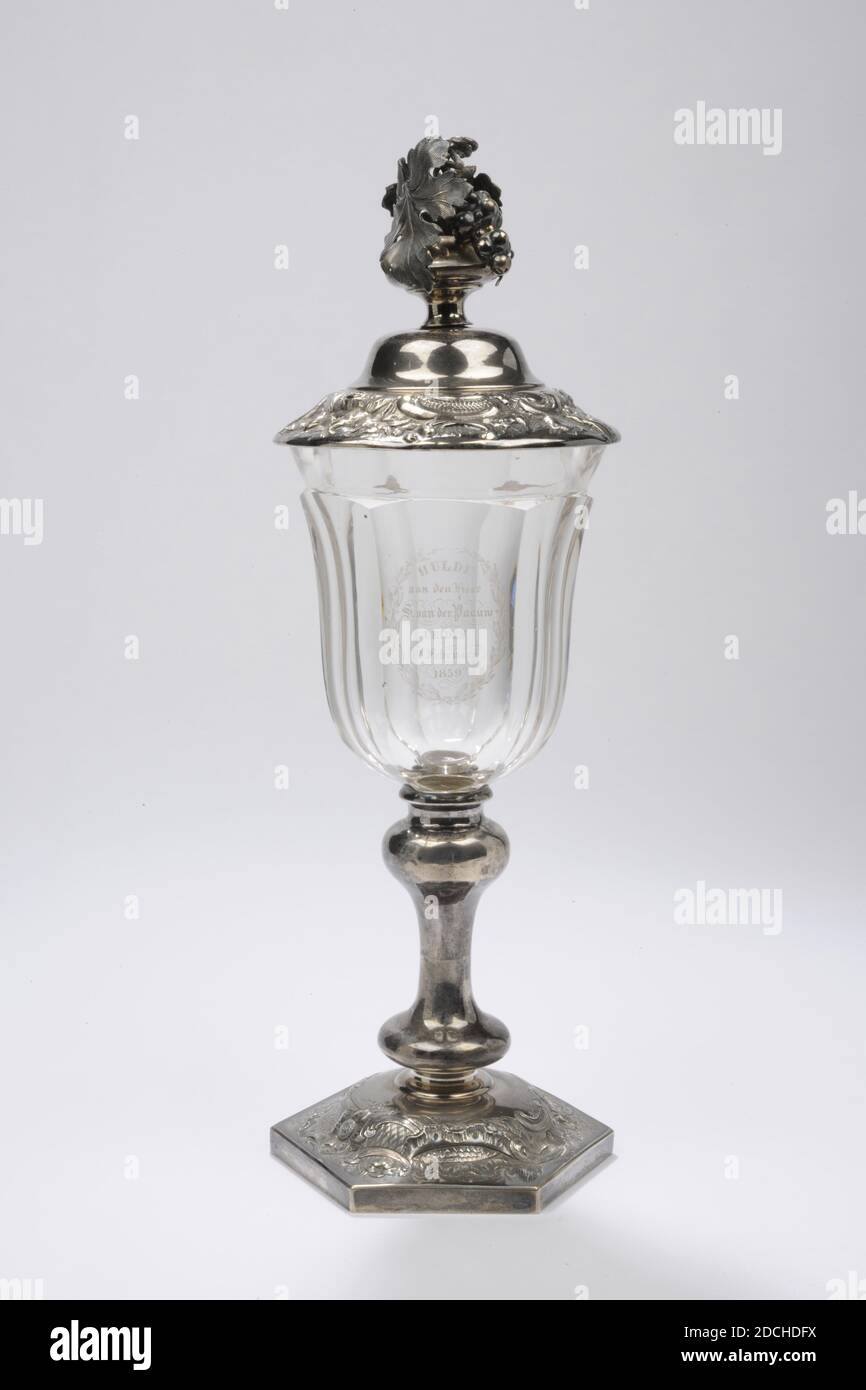 goblet, Zilverfabriek J.M. van Kempen en Zn, Voorschoten, 1858, silver, glass, Bowl and lid: 33.5 x 11.4cm 335 x 114mm, Bowl: 24.3 x 11.6cm 243 x 116mm, Lid: 9.5 x 11.4cm 95 x 114mm, diam. chalice: 10.4 cm / diam. base: 11.3 cm, crystal bowl with silver lid and silver base. The goblet has a hexagonal arched foot, which is decorated on top with engraving and gearing, depicting flower, leaf and ornamental motifs. The silver trunk is made up of a disc-shaped base nodule, a smooth stem and an inverted baluster-shaped knot. The chalice-shaped cup is made of thick glass and cut in six facets. Above Stock Photo