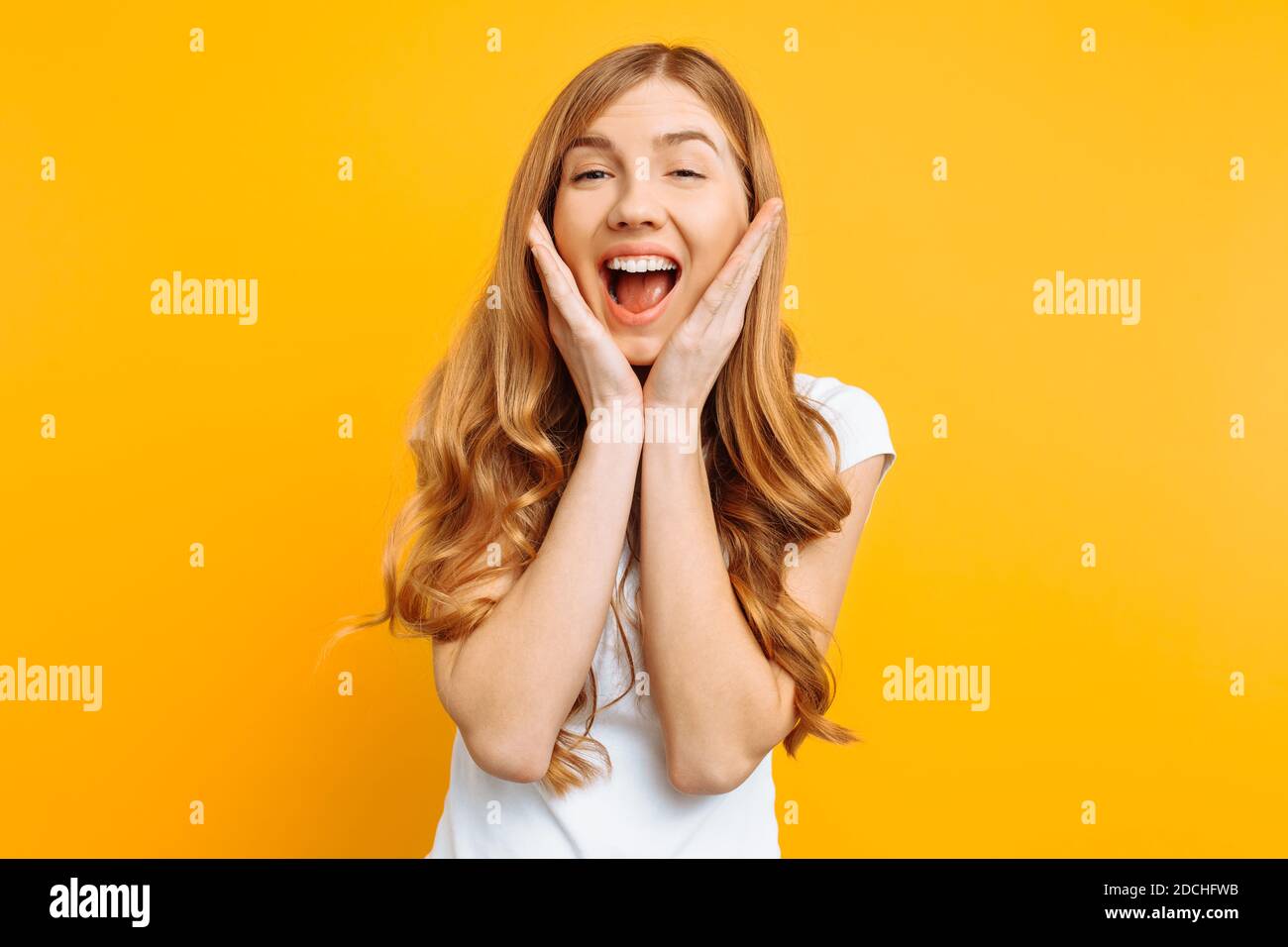 Portrait of an enthusiastic young girl screaming with joy over yellow background Stock Photo
