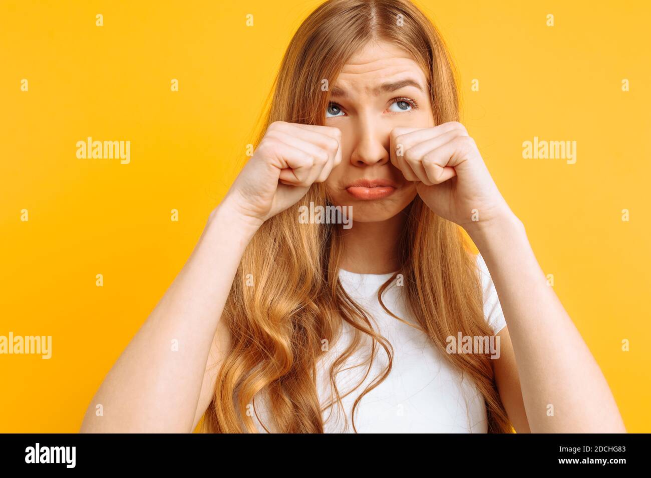 beautiful girl upset, woman crying on yellow background, bad mood Stock Photo