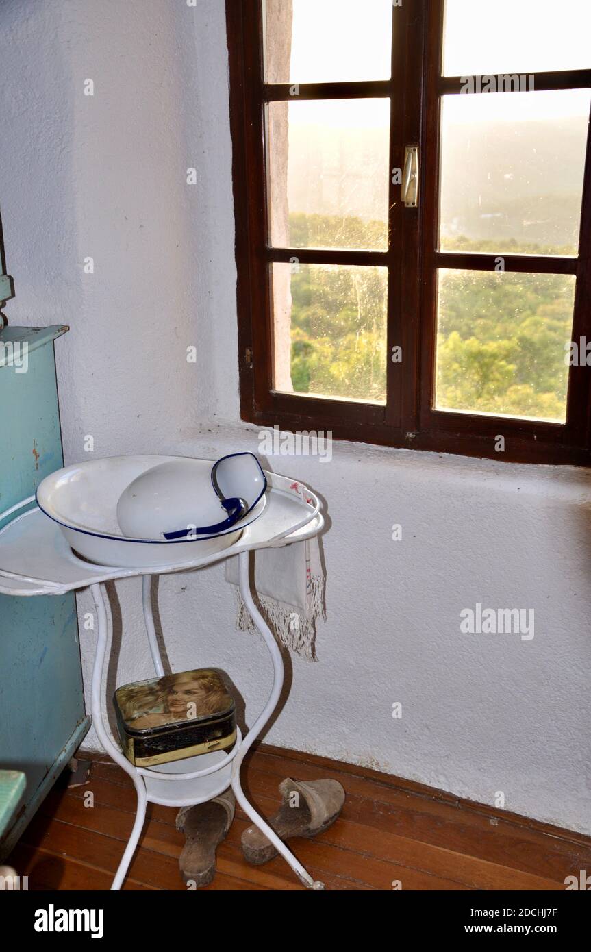 Grobnik, Croatia August 2020.Metal white Wash Basin Stand With Pitcher. Old wash basin on a stand.Metal white retro wash basin on a stand and a window. Stock Photo