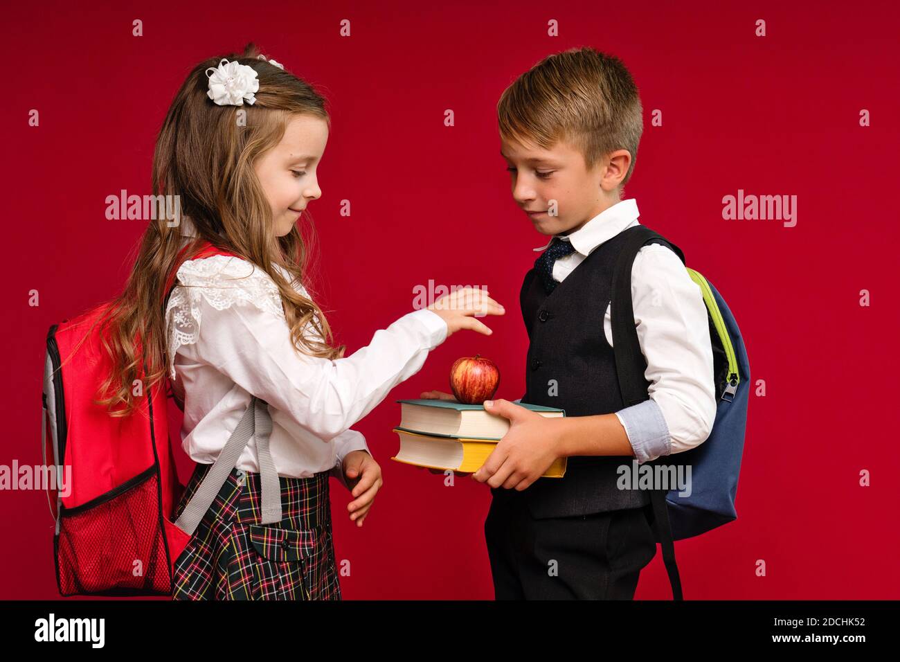 Preteens in school uniform carry backpacks on vivid red colored background. Knowledge day. Back to school. Education and study. Knowledge skills. September 1. School time. Stock Photo