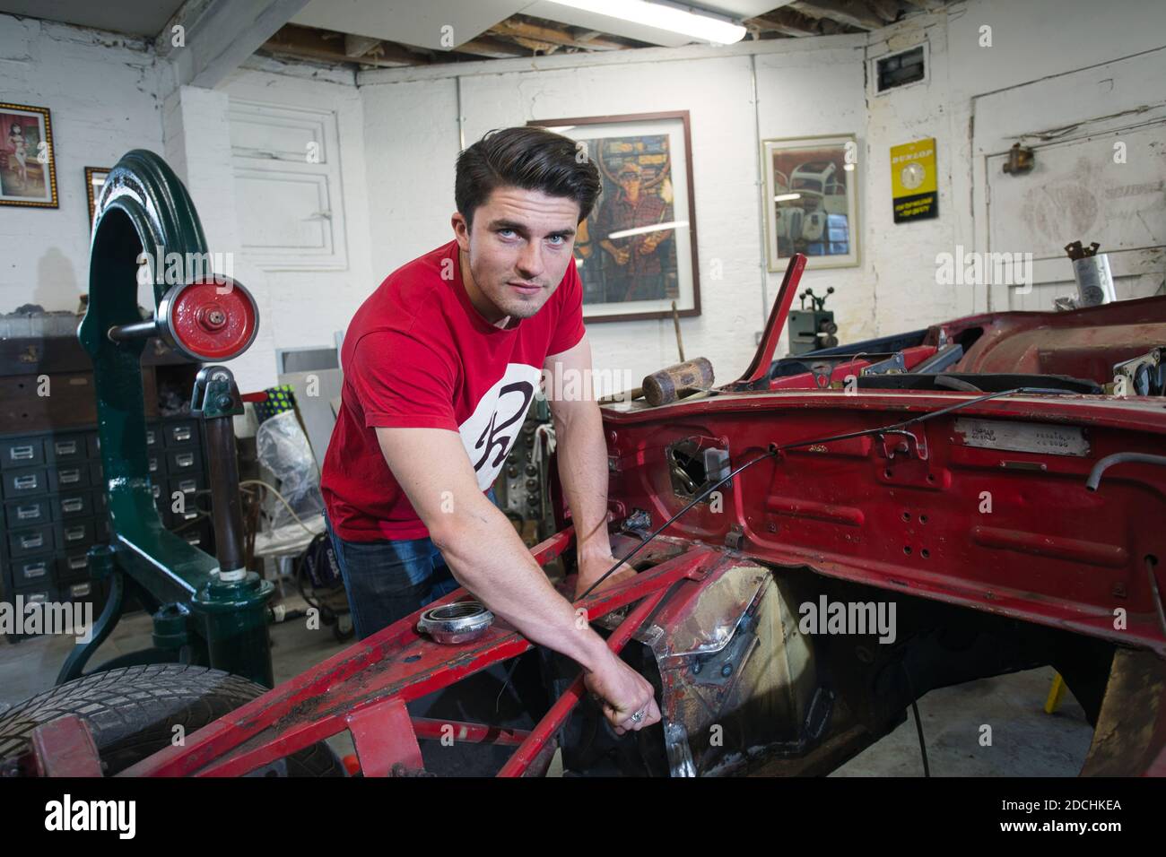 Good looking car mechanic working in garage on repair of old timer Stock Photo