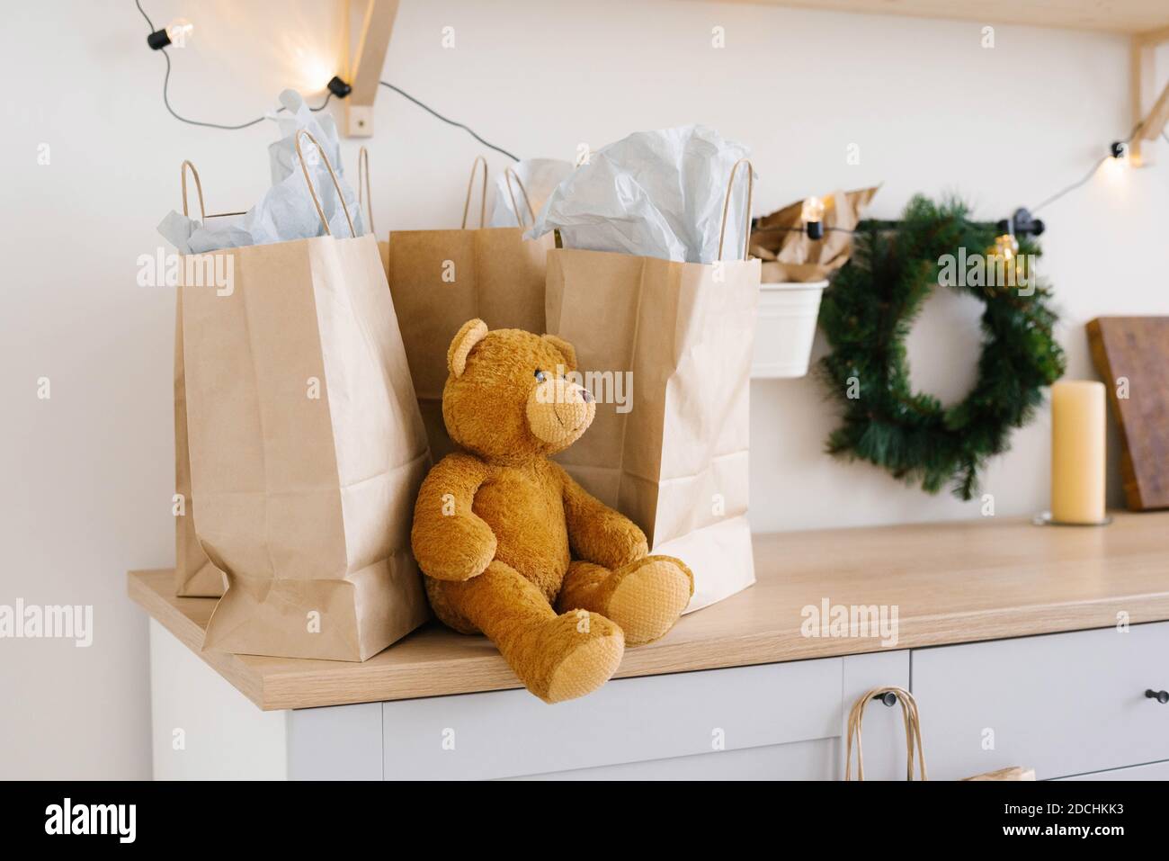Soft toy bear near craft paper bags and Christmas wreath Stock Photo