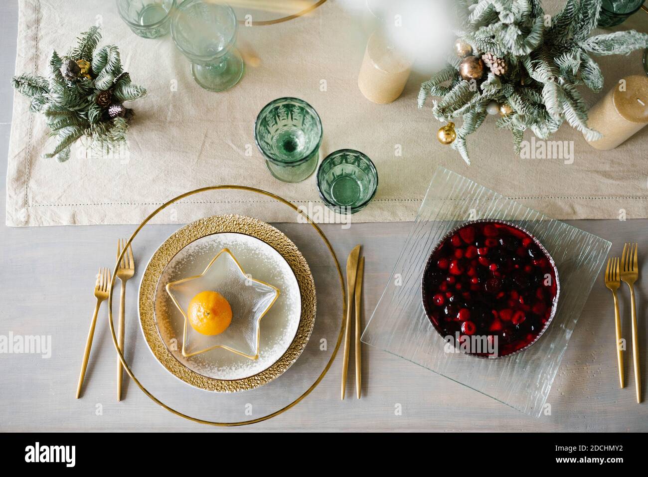 Stylish Christmas dinner setting. Gold and white plates, a star-shaped plate  with tangerine. Berry pie on the table Stock Photo - Alamy