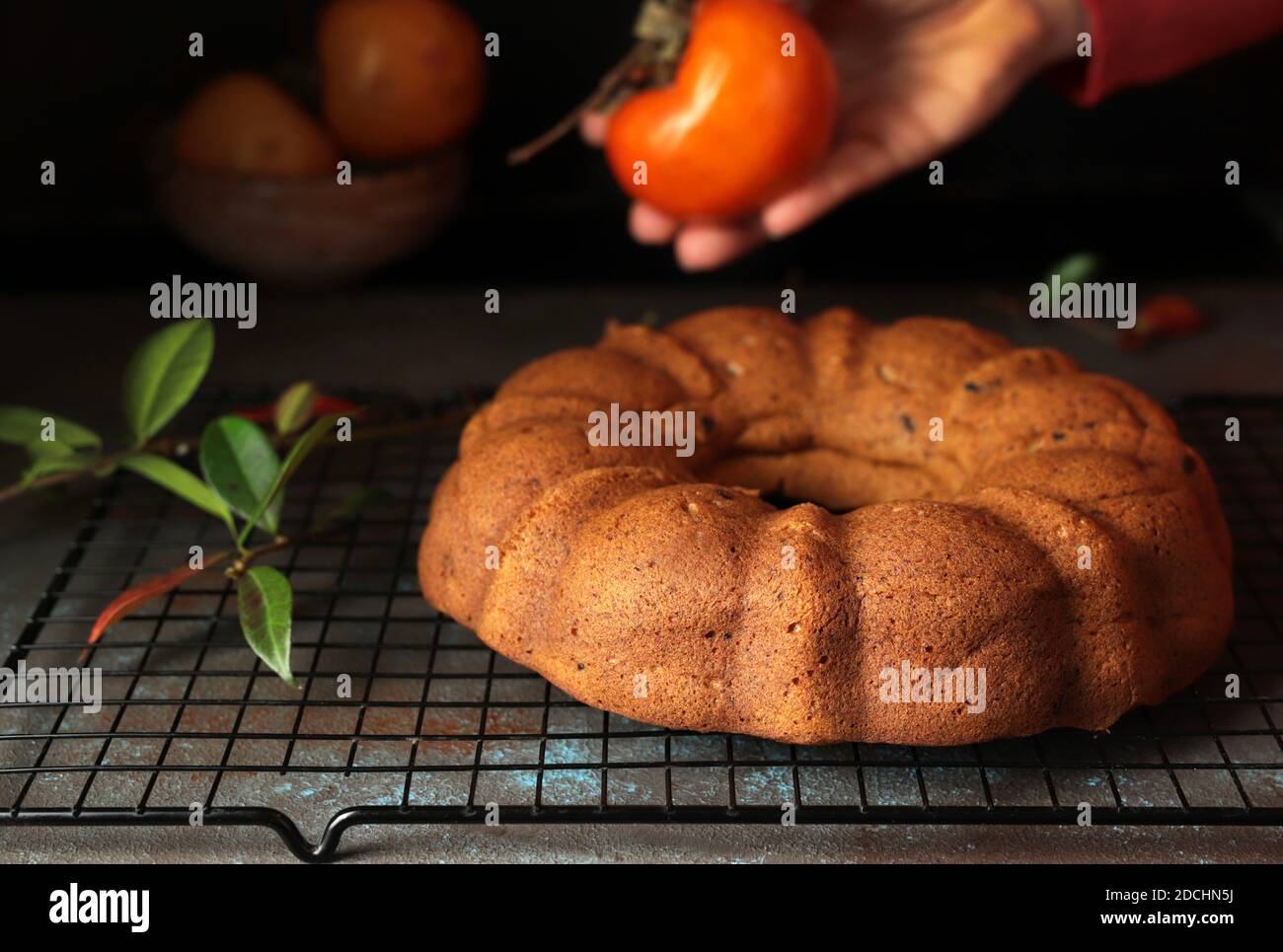 Bundt cake with persimmon, served on table. Selective focus. Stock Photo