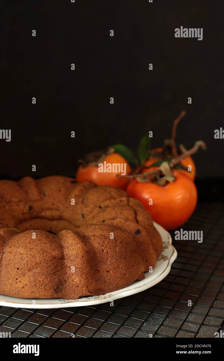 Bundt cake with persimmon, served on table. Selective focus. Stock Photo