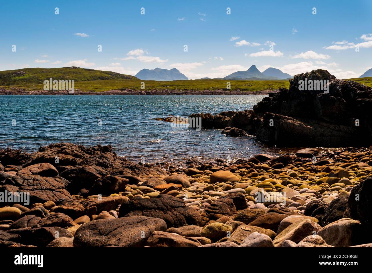 A view across Achnahaird Bay to the distant mountains of Sulvein, Stac Pollaidh and Cùl Beag, on the north west coast of Scotland. June. Stock Photo
