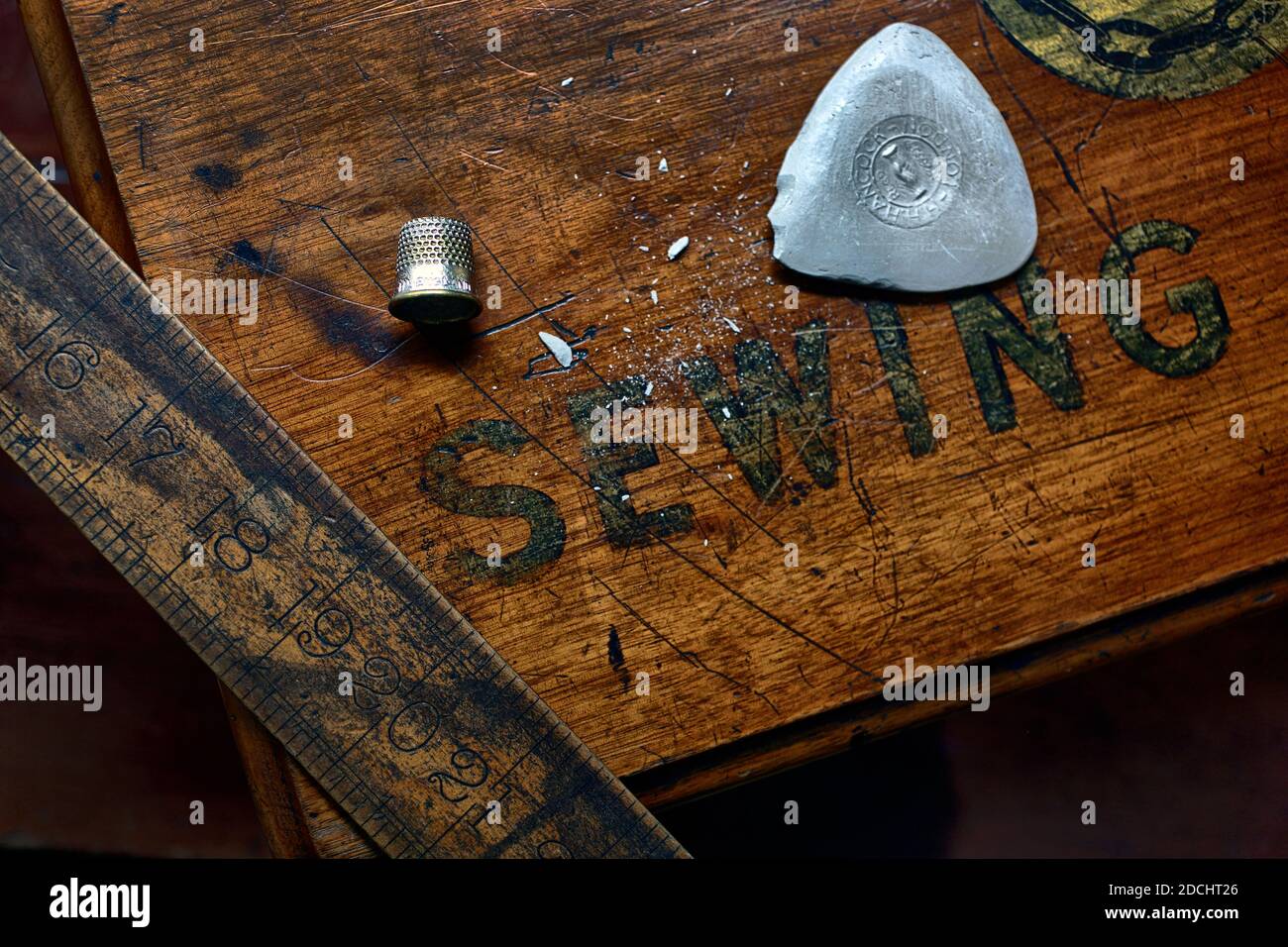 Wooden scale,chalk and thimble on wooden sewing table close up view at Dege & Skinner. Stock Photo