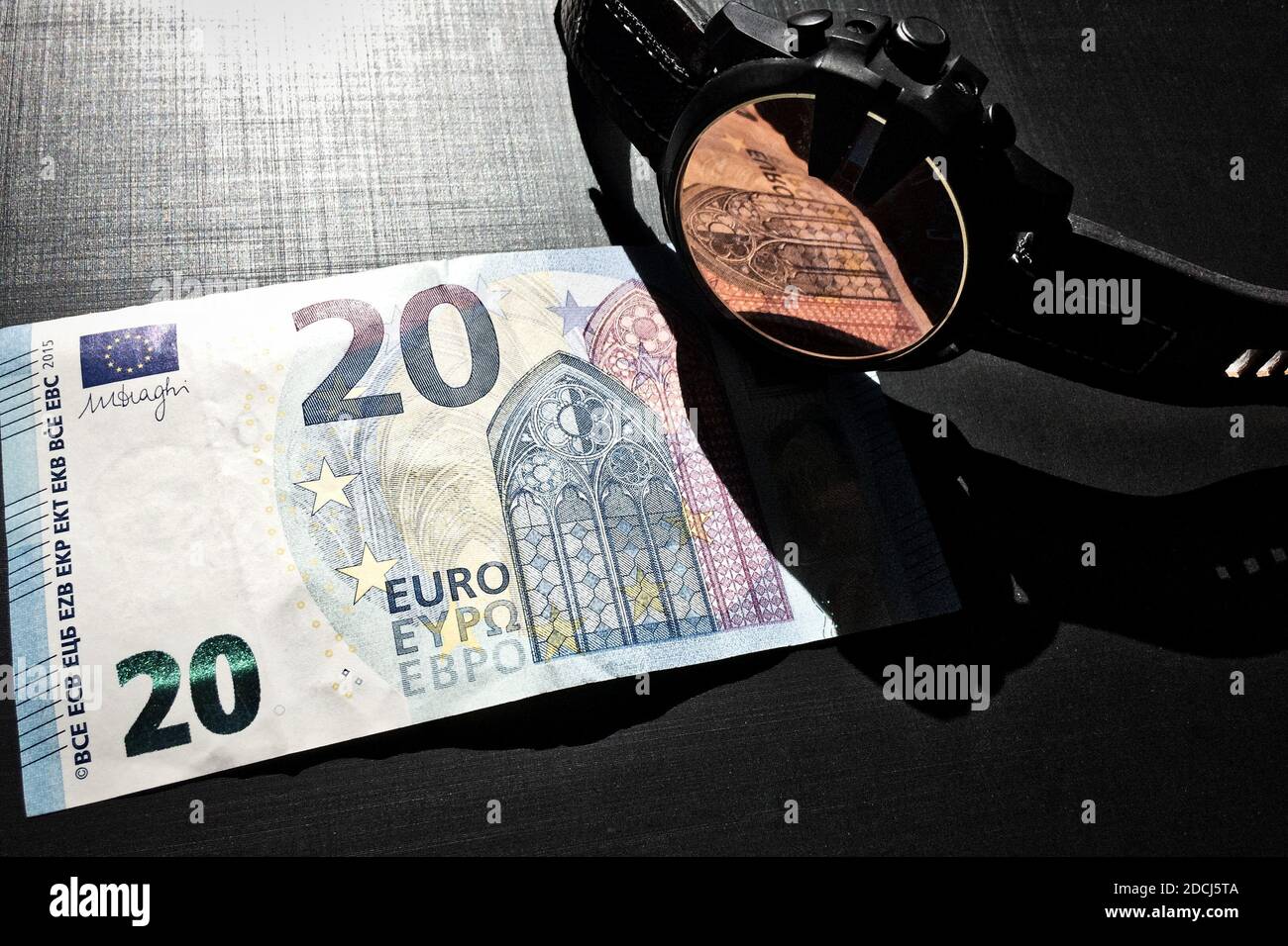 wrist watch with leather strap near the banknote on a dark background, watch on top of money, time is money, wristwatch, European currency, twenty eur Stock Photo