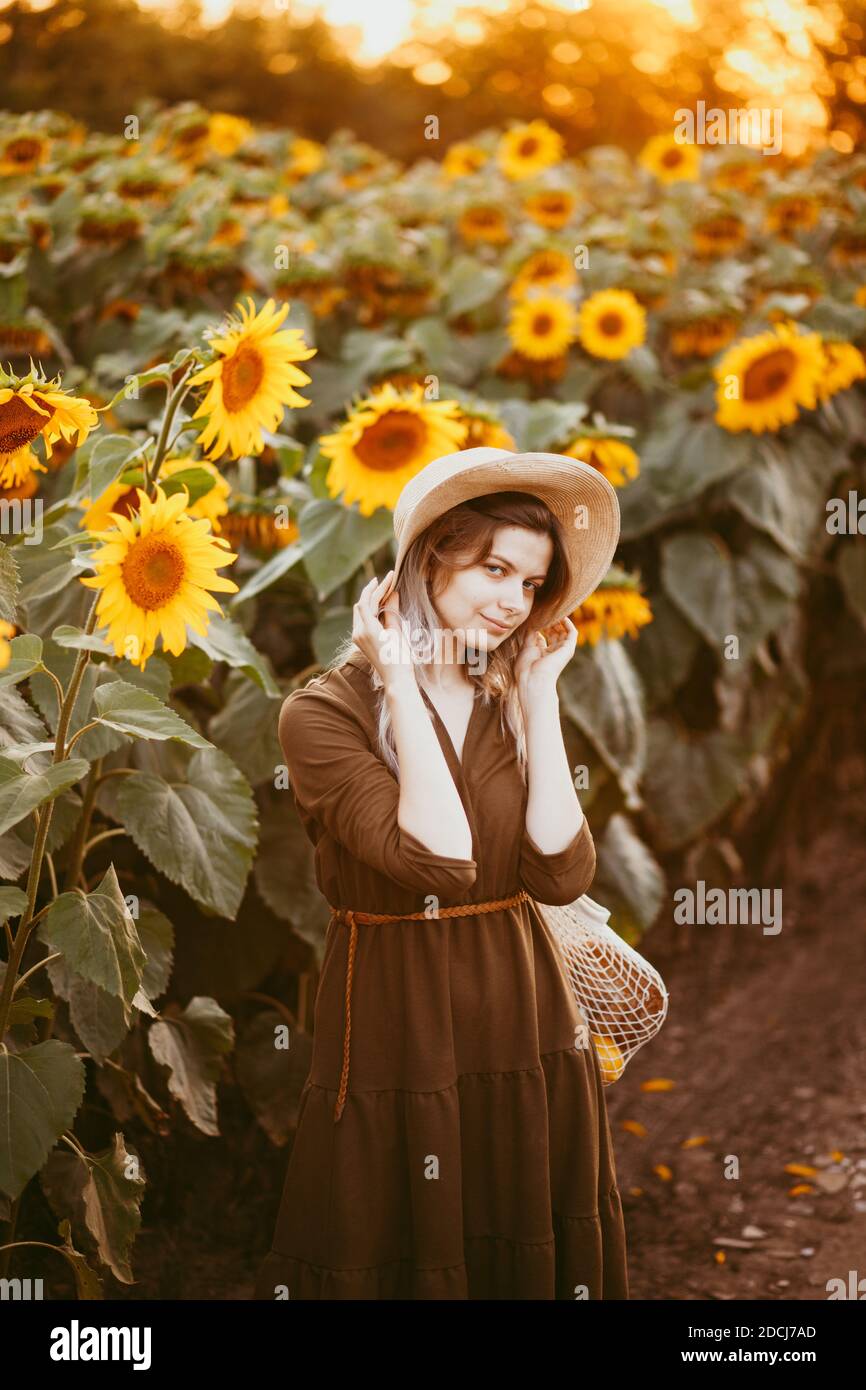 beautiful girl in a field of sunflowers with a bag of food in her hands ...