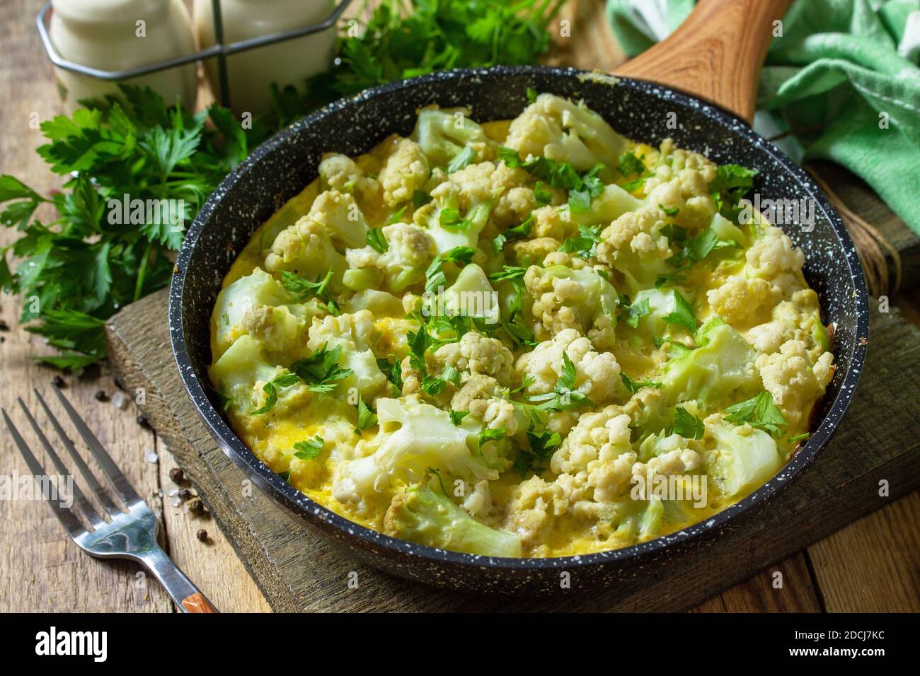 Diet breakfast or healthy lunch. Egg omelet with cauliflower in a cast-iron pan on rustic wooden table. Stock Photo
