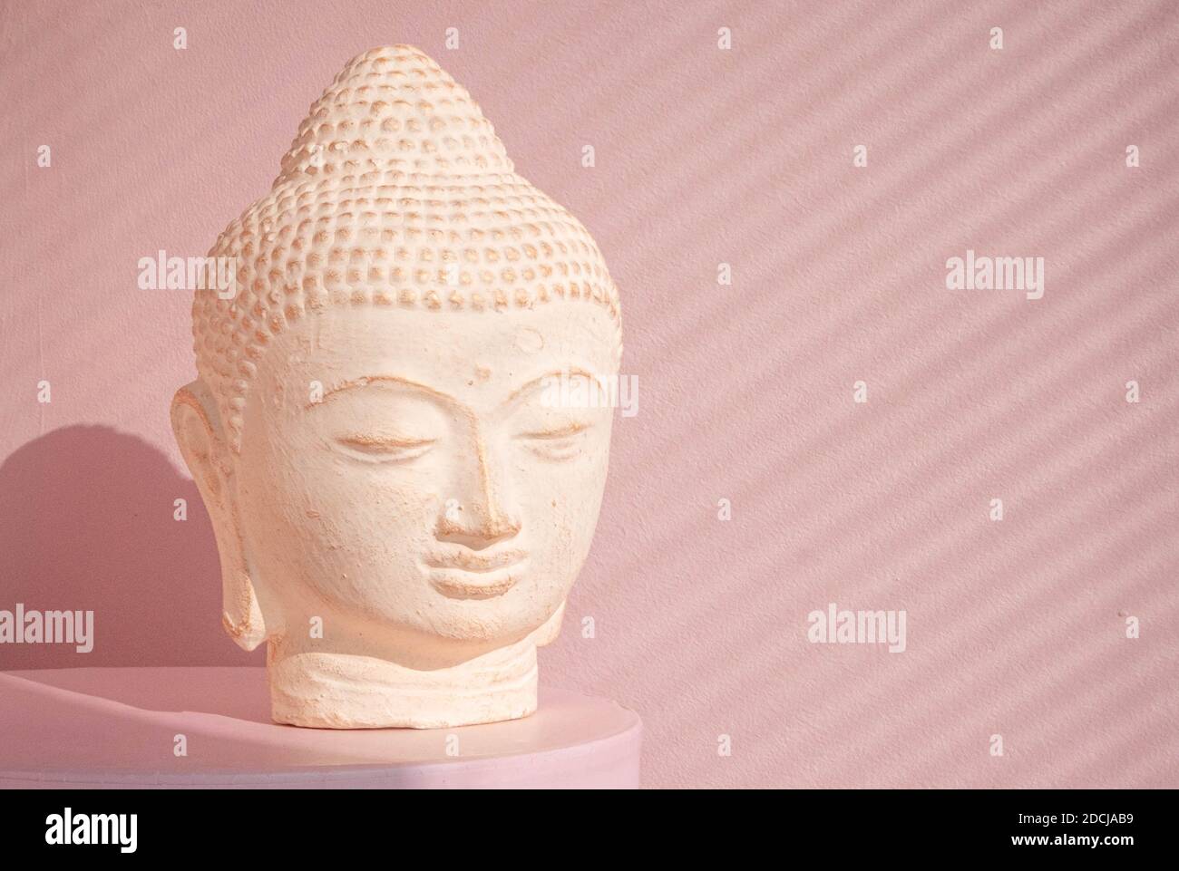 White Buddha bust on pastel pink background Stock Photo